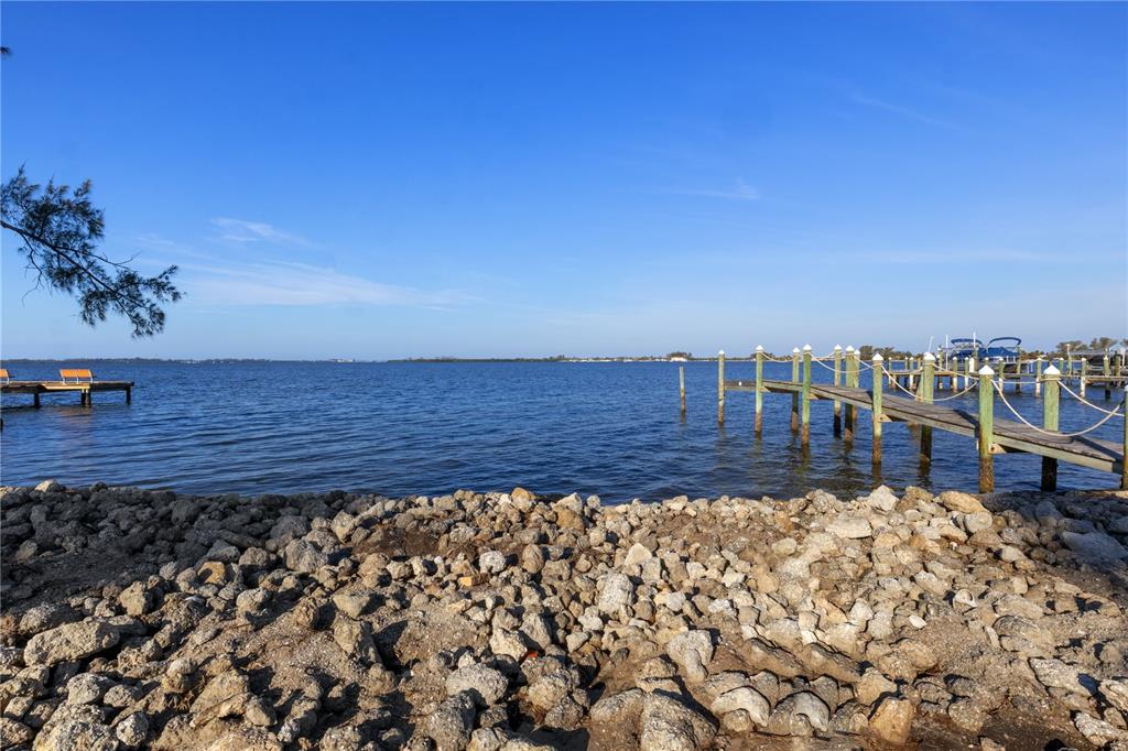 A rocky shoreline overlooks a calm bay with two wooden boat docks — 712 PALMA SOLA BOULEVARD, BRADENTON, FL