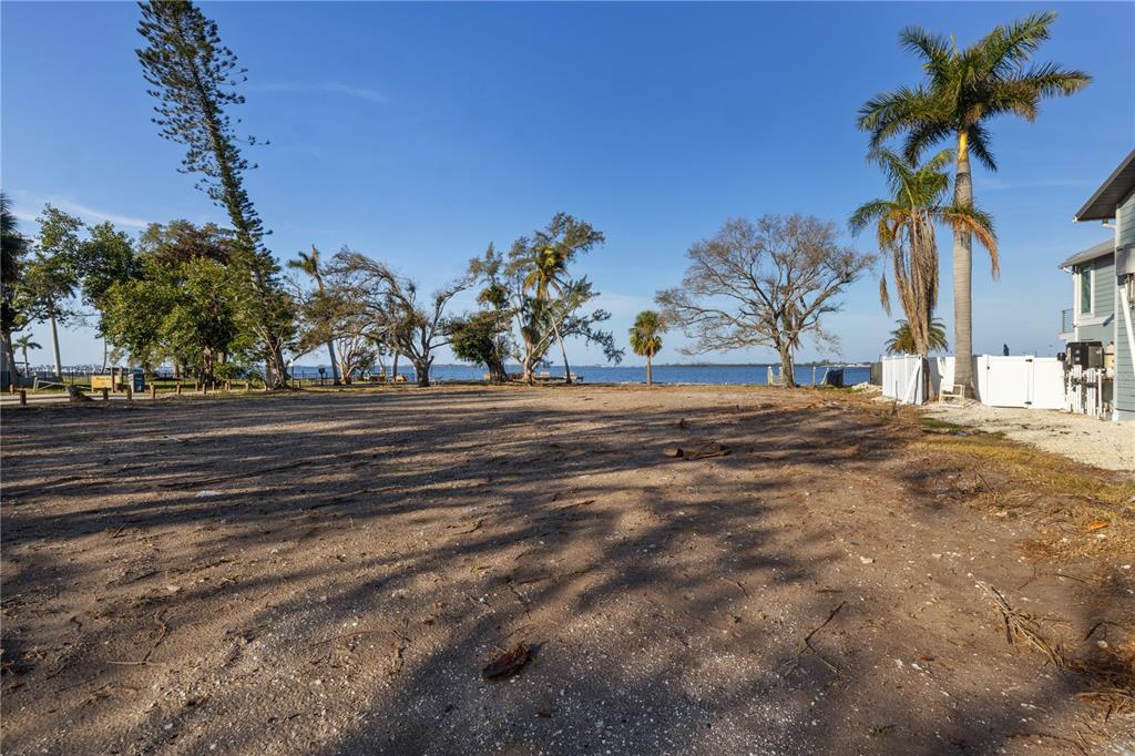 A vacant, sandy waterfront lot features scattered trees and a view of the open water — 712 PALMA SOLA BOULEVARD, BRADENTON, FL