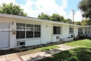 The exterior of a white, single-story residential building features multiple windows and a paved walkway — 190 NE 90th St # 2, El Portal FL 33138, EL PORTAL, FL