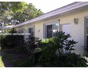The exterior of a single-story light yellow building features a white door and large windows — 190 NE 90th St # 2, El Portal FL 33138, EL PORTAL, FL