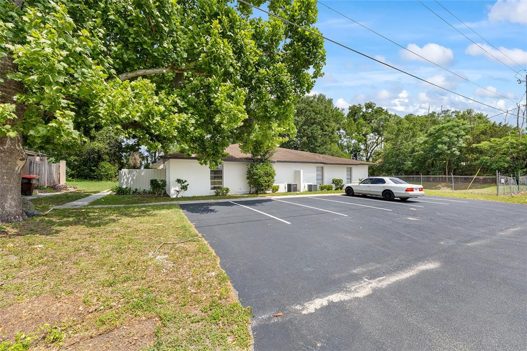A white single-story building sits behind an asphalt parking lot with a large tree — 3025 SE 55TH AVENUE, OCALA, FL