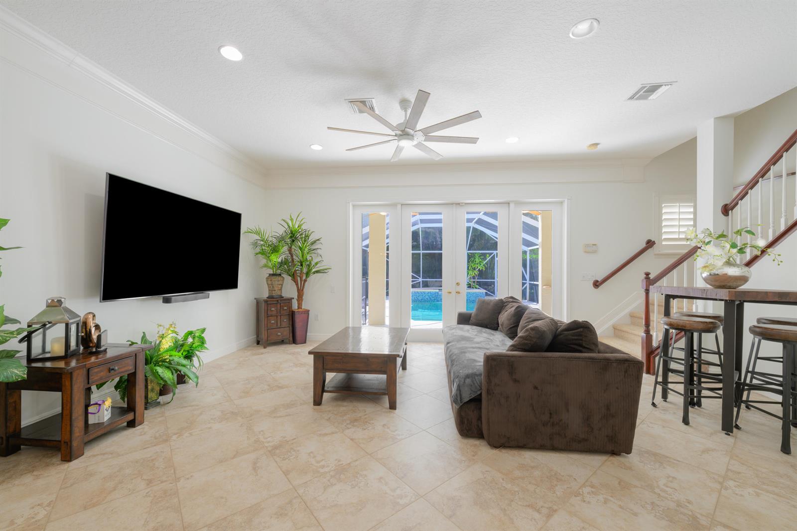 A living room features a large television, brown sofa, coffee table, and sliding glass doors — 742 Cable Beach Lane, West Palm Beach FL 33410, WEST PALM BEACH, FL
