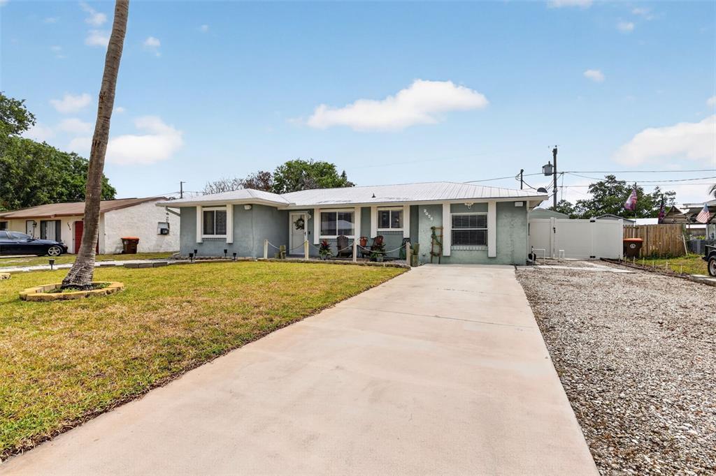 A single-story house with a light gray exterior, a concrete driveway, and a palm tree — 2026 7TH COURT SW, VERO BEACH, FL