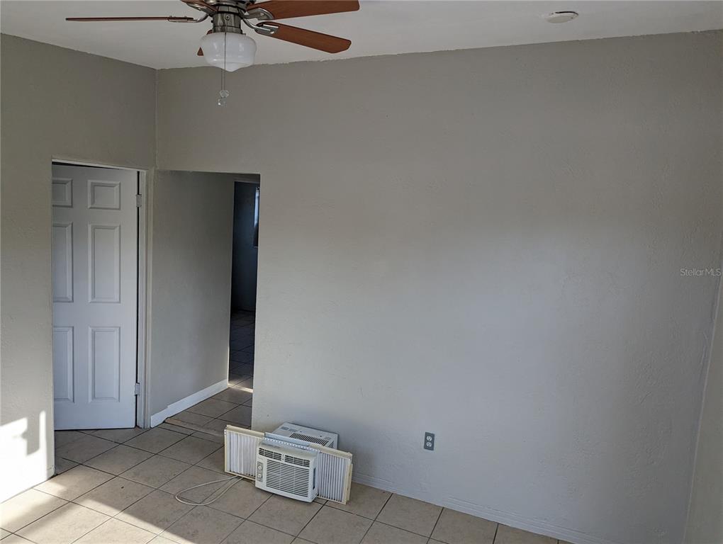 A room with light gray walls, tile flooring, a ceiling fan, and a window air conditioner — 2000 QUEENSBORO AVENUE S UNIT A, ST PETERSBURG, FL