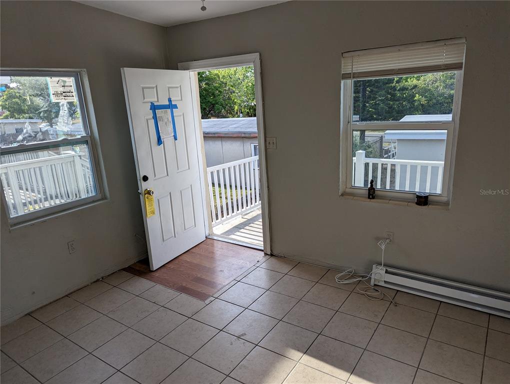 A room with tiled floors, two windows, and an open door leading to a deck — 2000 QUEENSBORO AVENUE S UNIT A, ST PETERSBURG, FL