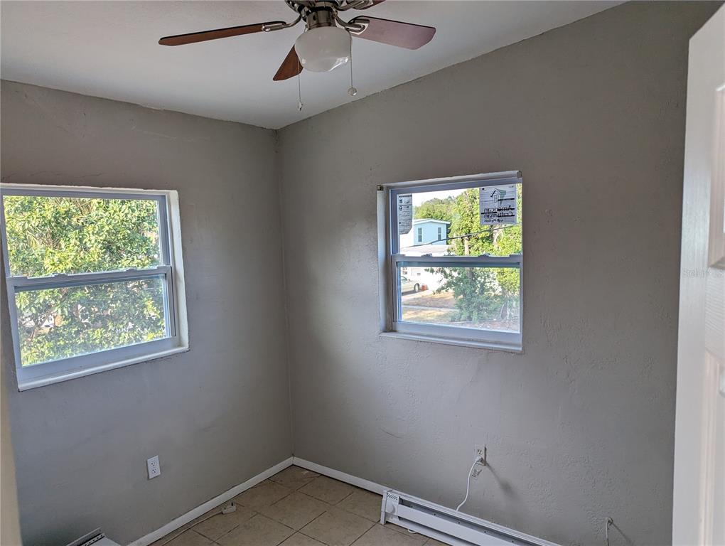 A small bedroom features gray walls, tile flooring, a ceiling fan, and two windows — 2000 QUEENSBORO AVENUE S UNIT A, ST PETERSBURG, FL