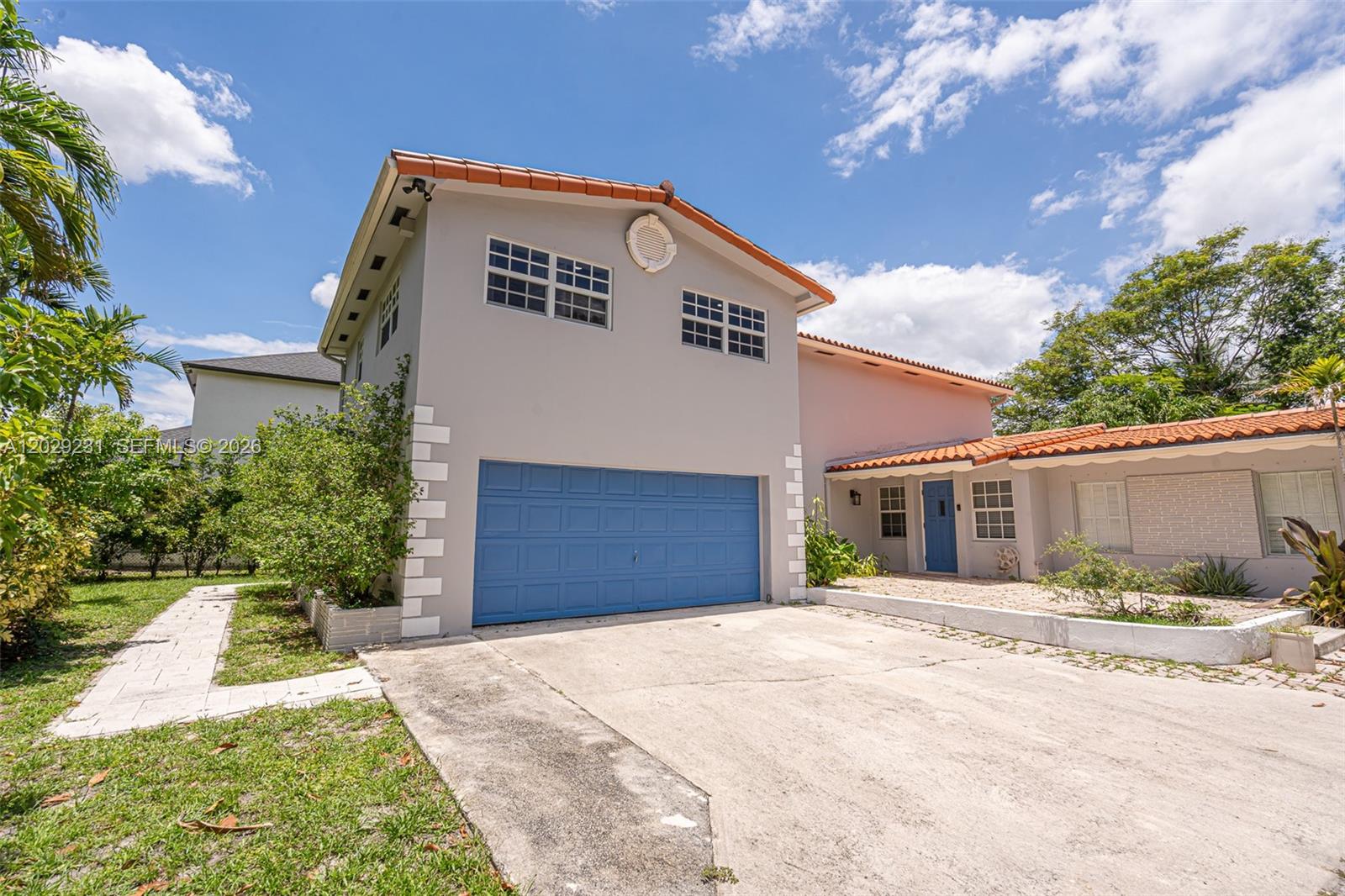 A two-story house with a blue garage door, a tiled roof, and a concrete driveway — 5613 Pierce St # 1, Hollywood FL 33021, HOLLYWOOD, FL