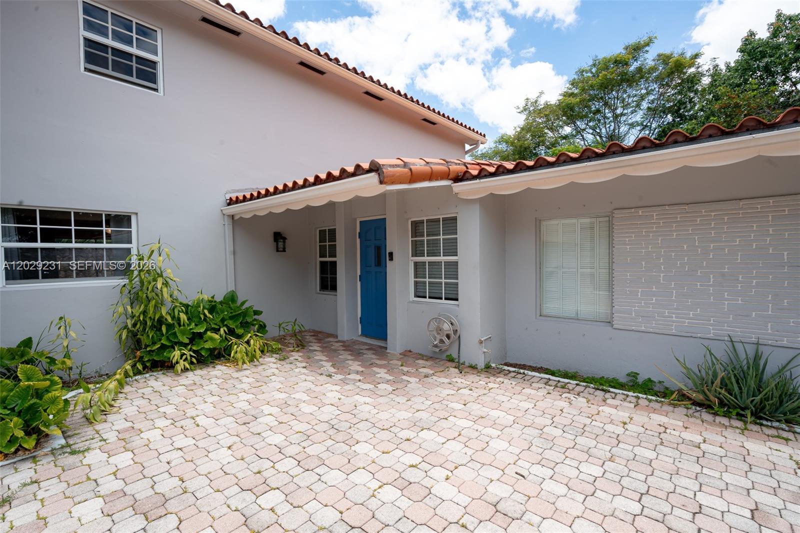A paved courtyard leads to a blue front door under a terracotta-tiled roof overhang — 5613 Pierce St # 1, Hollywood FL 33021, HOLLYWOOD, FL