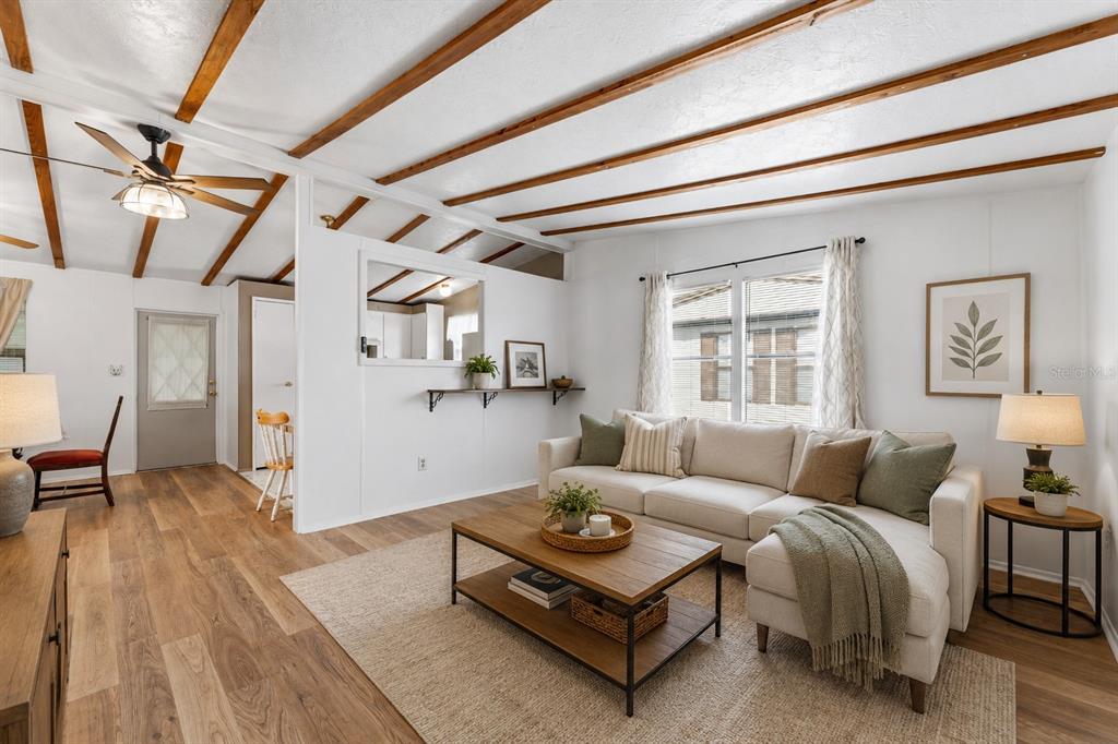 A living room features wood-look flooring, exposed ceiling beams, a sectional sofa, and a coffee table — 34334 COUNTRYSIDE DRIVE, WESLEY CHAPEL, FL
