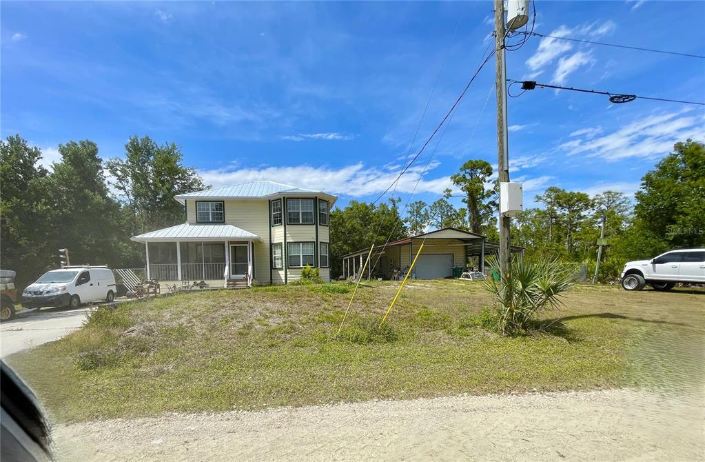 A two-story yellow house with a wraparound porch and a detached garage — 27213 HACIENDA DRIVE, PUNTA GORDA, FL