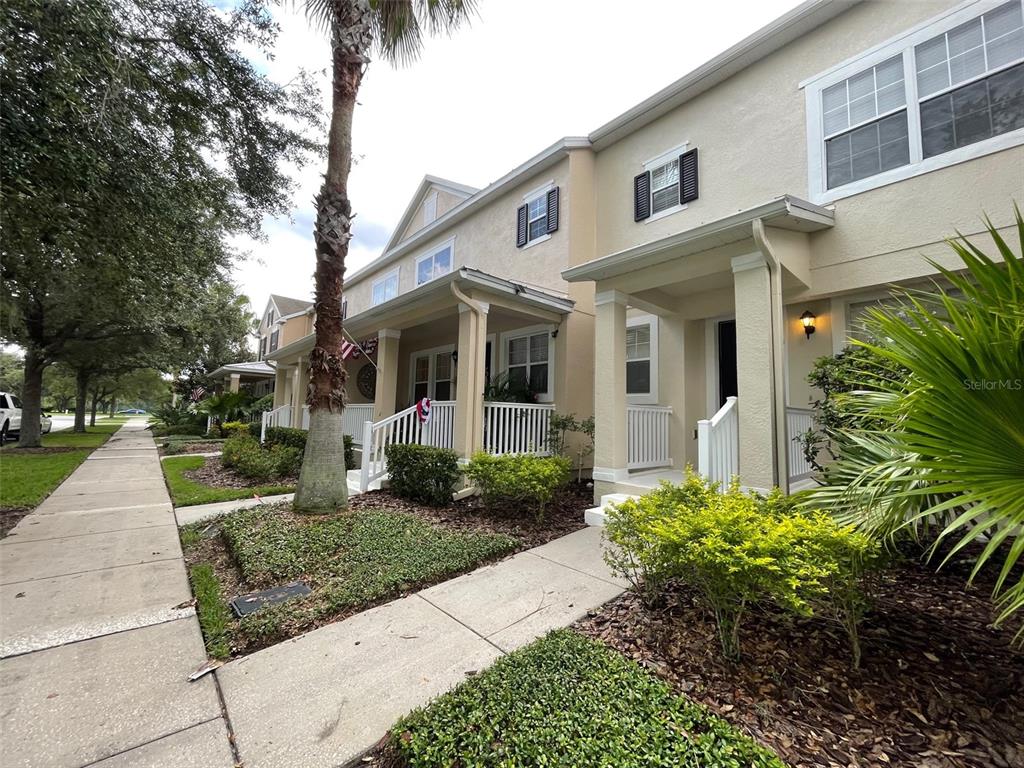 A row of tan townhouses with white railings and palm trees along a sidewalk — 9236 CARDINAL MEADOW TRAIL, ORLANDO, FL
