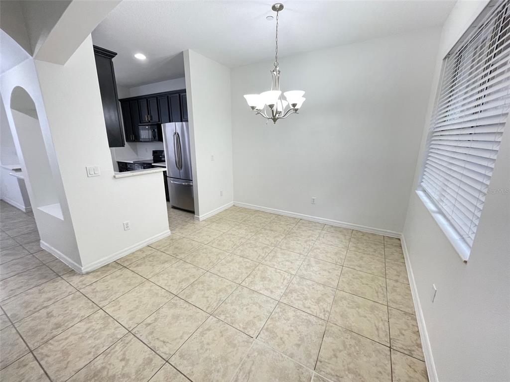 A dining area features tile flooring, a chandelier, and an adjacent kitchen with dark cabinets — 9236 CARDINAL MEADOW TRAIL, ORLANDO, FL