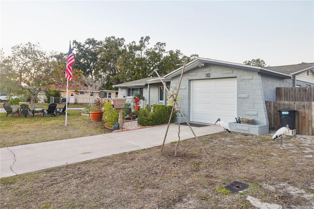 A gray brick house with a white garage door, a concrete driveway, and a front yard — 7615 CUMBER DRIVE, NEW PORT RICHEY, FL