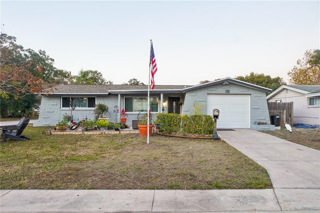 A single-story house with a gray stone facade, a one-car garage, and a front lawn — 7615 CUMBER DRIVE, NEW PORT RICHEY, FL
