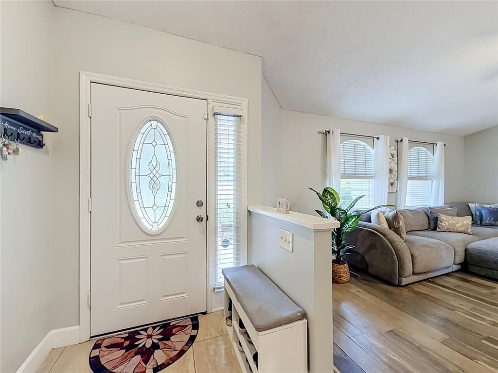 An entryway features a white front door with a glass oval insert and a shoe bench — 218 GLENRIDGE LOOP N, LAKELAND, FL