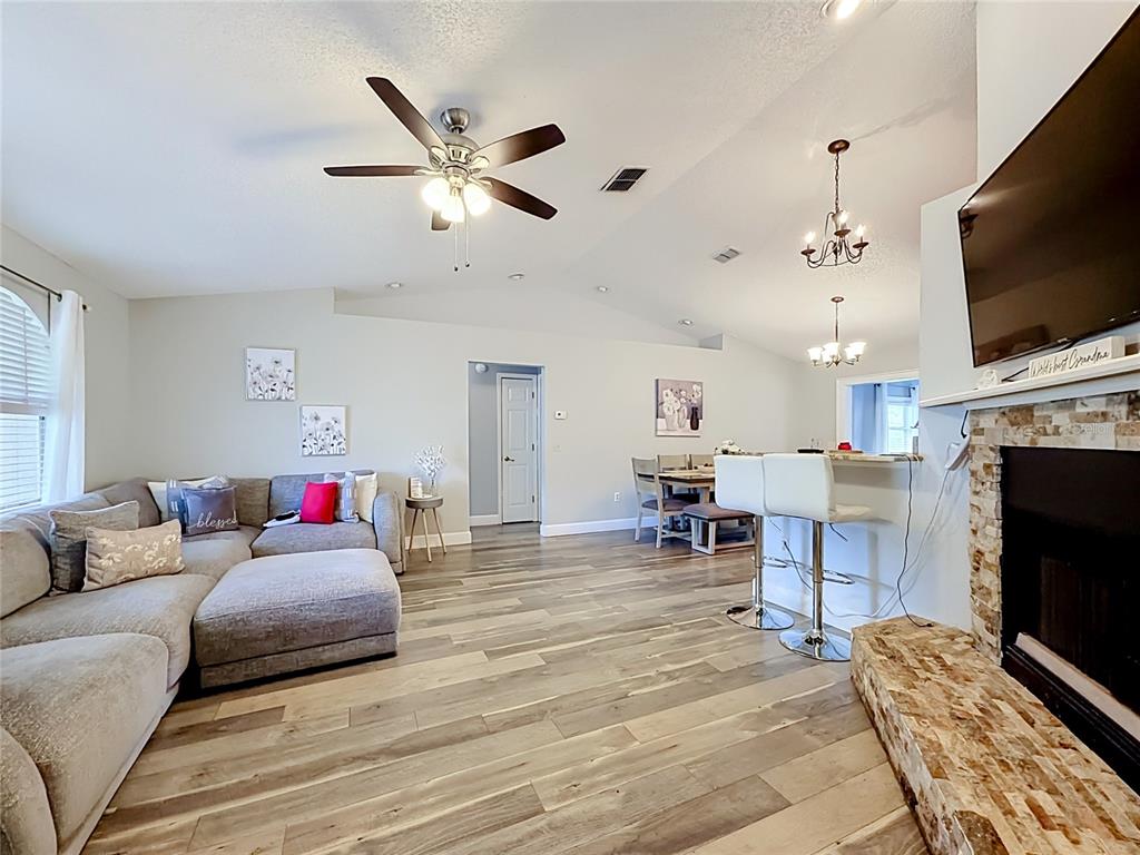 A living room features wood-look flooring, a sectional sofa, a fireplace, and an open kitchen — 218 GLENRIDGE LOOP N, LAKELAND, FL