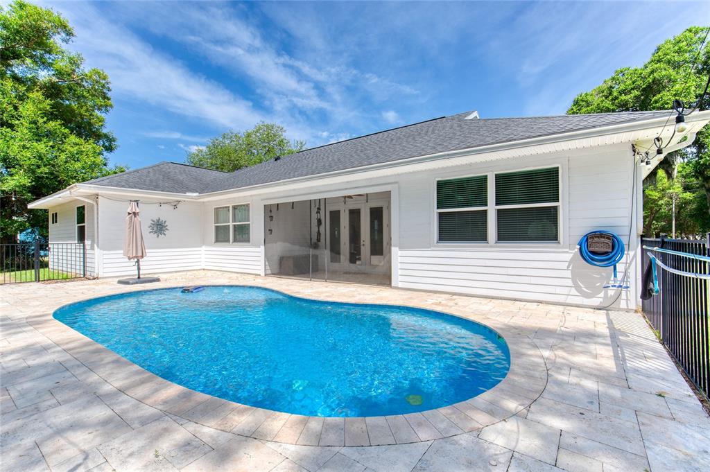 A white house with a dark shingled roof overlooks a kidney-shaped swimming pool and patio — 15 MAPLE STREET, FLAGLER BEACH, FL