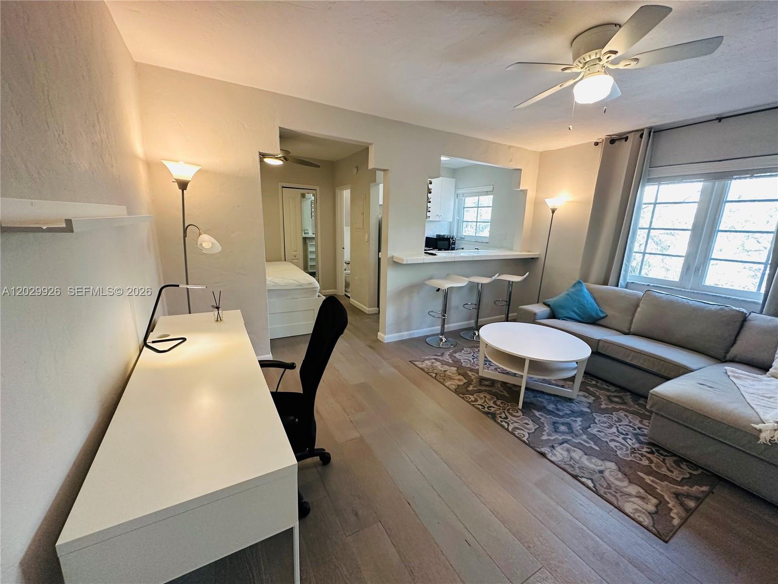 A living room features a desk, a sofa, a breakfast bar, and light wood flooring — 260 Euclid Ave # 27, Miami Beach FL 33139, MIAMI BEACH, FL