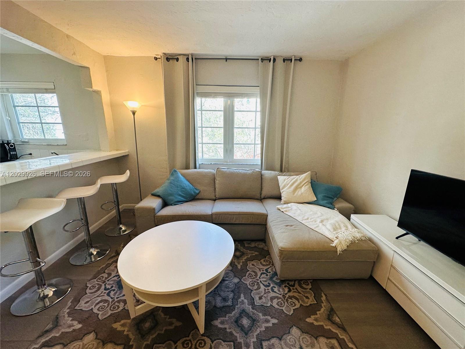 A living room features a sectional sofa, coffee table, television, and a breakfast bar — 260 Euclid Ave # 27, Miami Beach FL 33139, MIAMI BEACH, FL