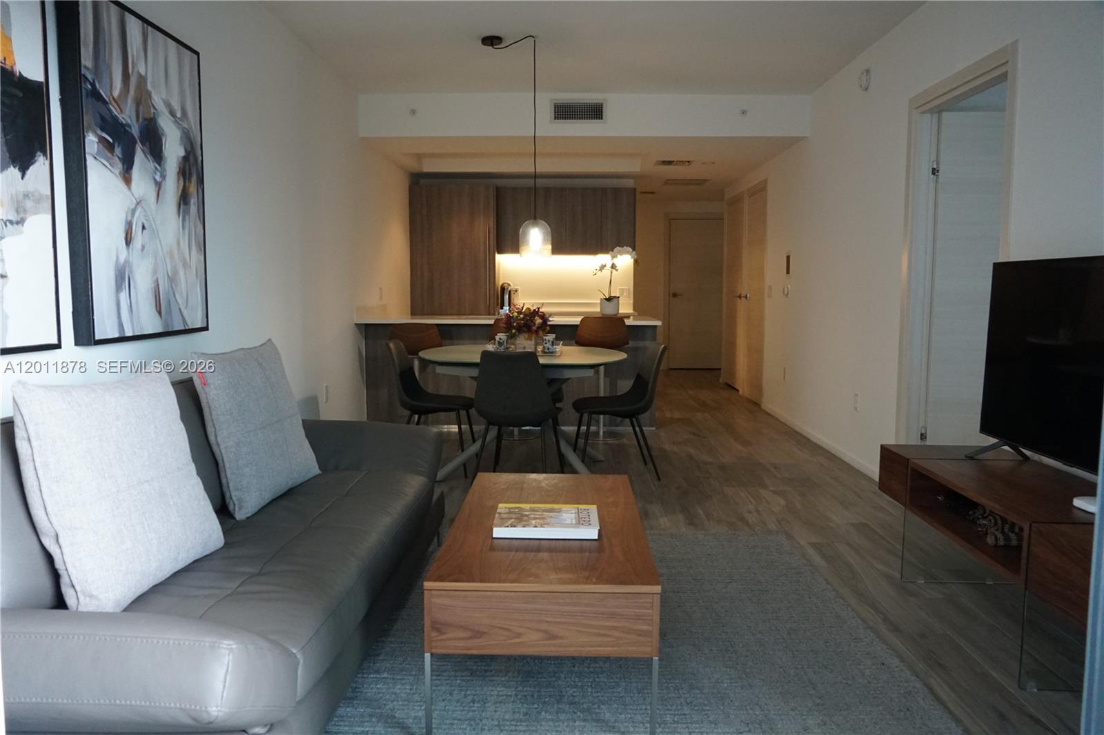 This living room features a gray sofa, a wooden coffee table, and an adjacent kitchen — 801 S Miami Ave # 2306, Miami FL 33130, MIAMI, FL