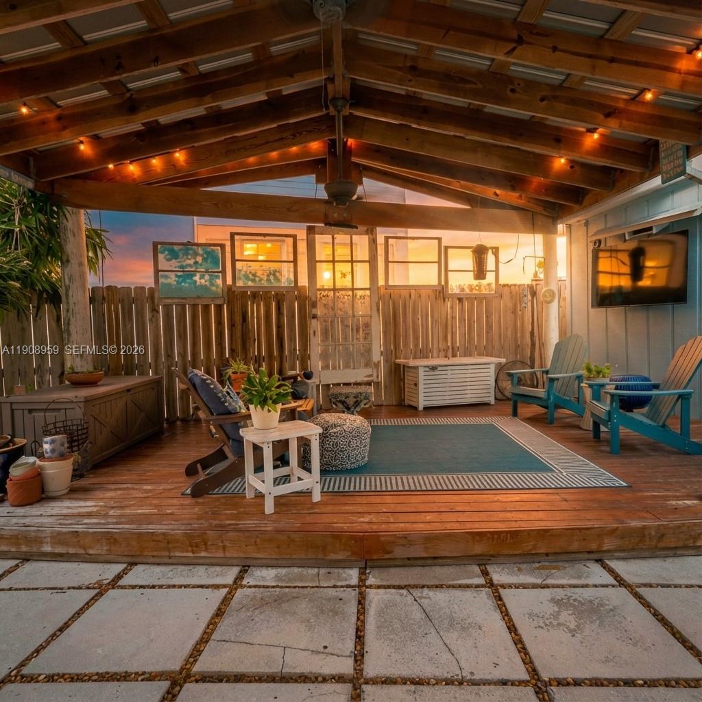 A covered wooden deck features outdoor seating, a rug, and a decorative fence with windows — 160 Ridge St, Tavernier FL 33070, TAVERNIER, FL