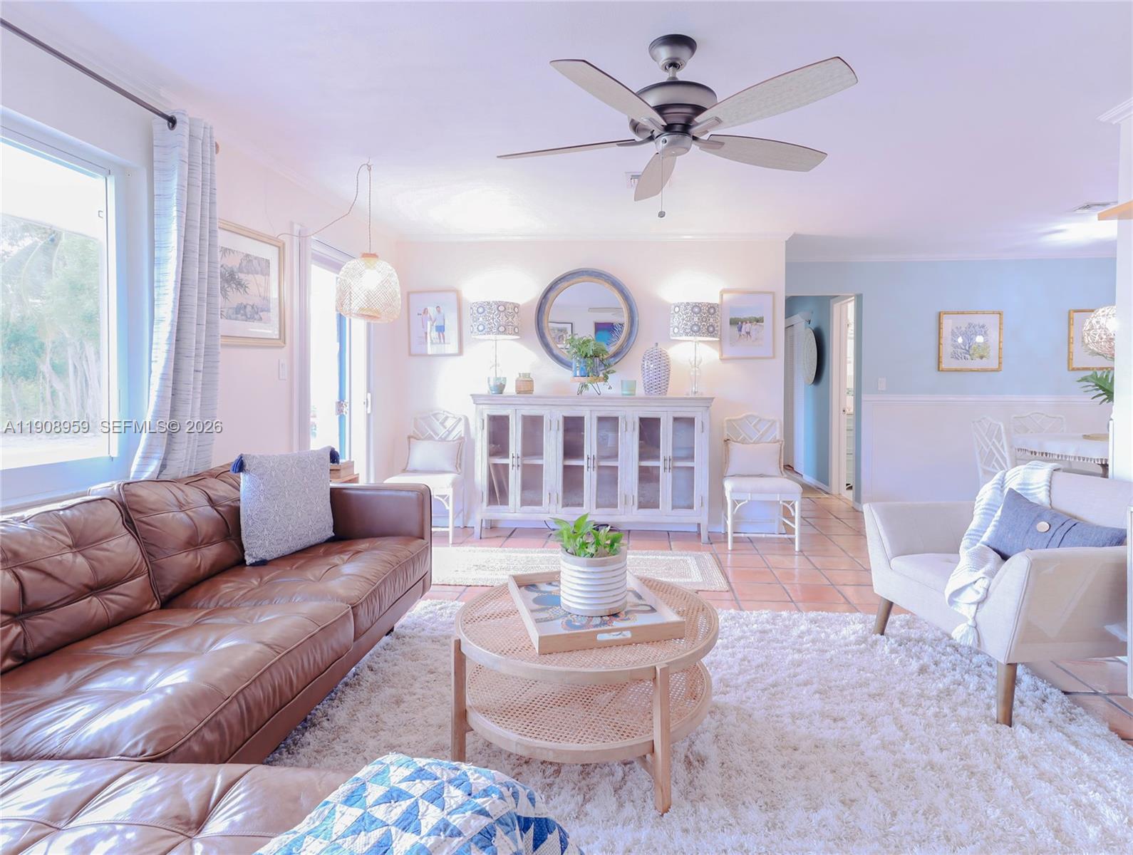 A living room features a brown leather sofa, a round rattan coffee table, and a sideboard — 160 Ridge St, Tavernier FL 33070, TAVERNIER, FL