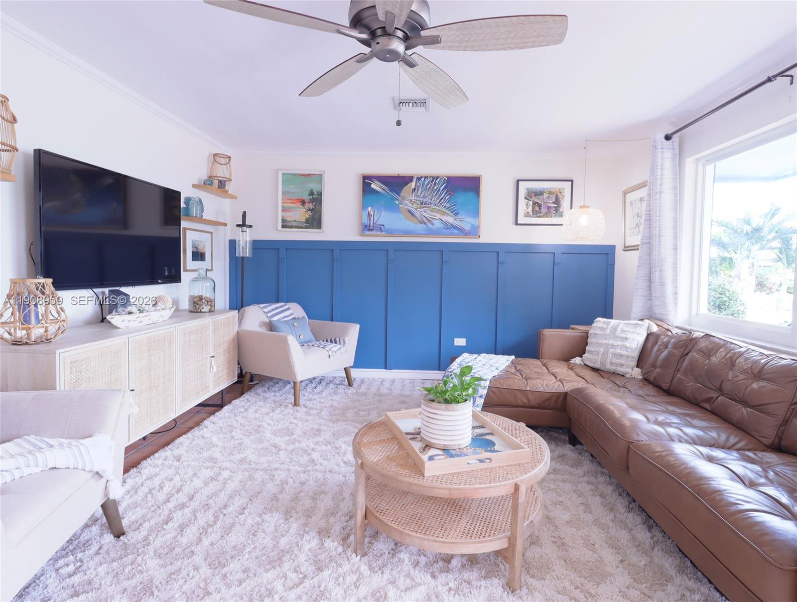 A living room features a blue paneled accent wall, brown leather sofa, and rattan furniture — 160 Ridge St, Tavernier FL 33070, TAVERNIER, FL