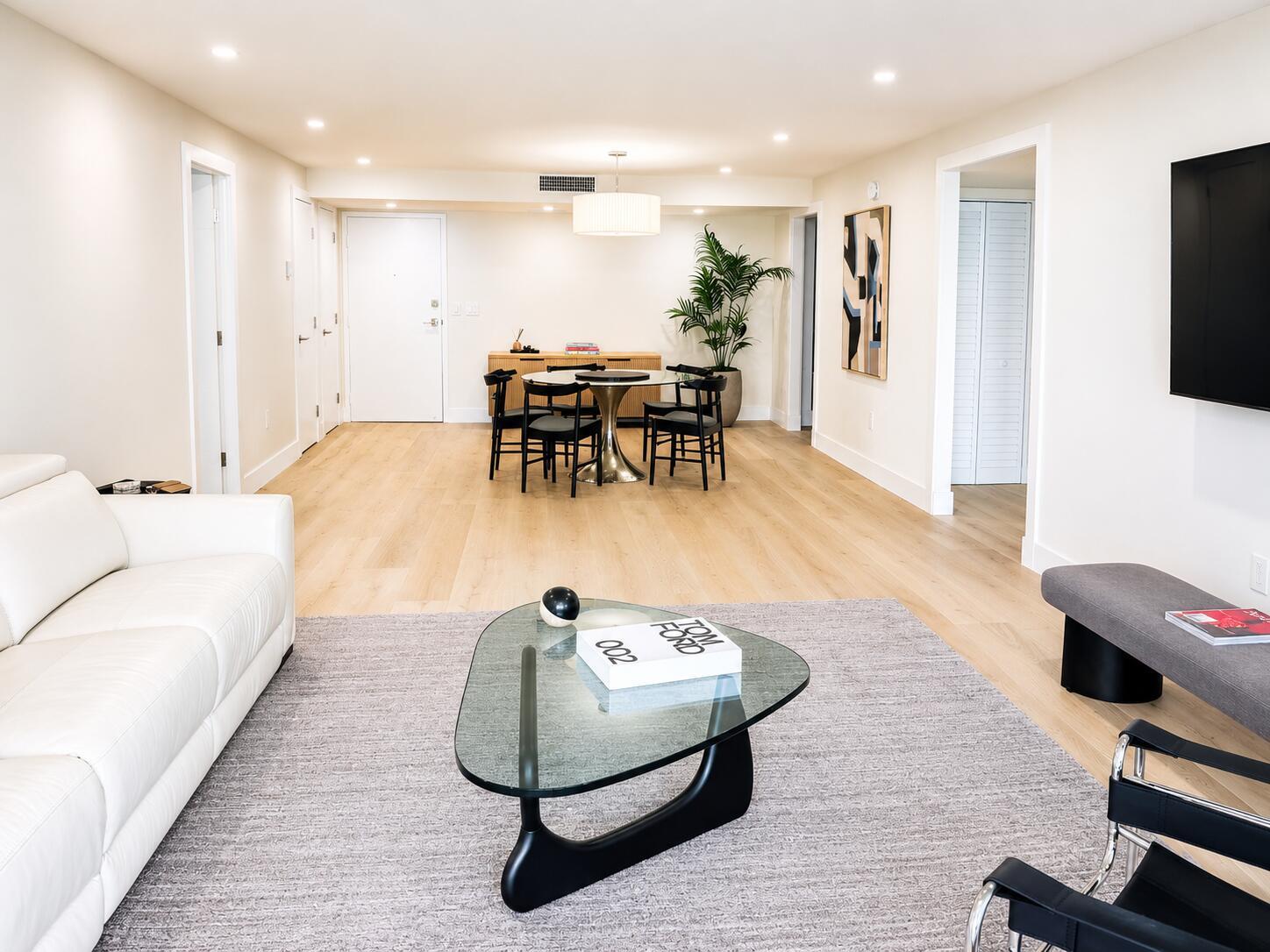 A living and dining area with light wood floors, a white sofa, and glass coffee table — 3460 S Ocean Boulevard # 4150, Palm Beach FL 33480, PALM BEACH, FL