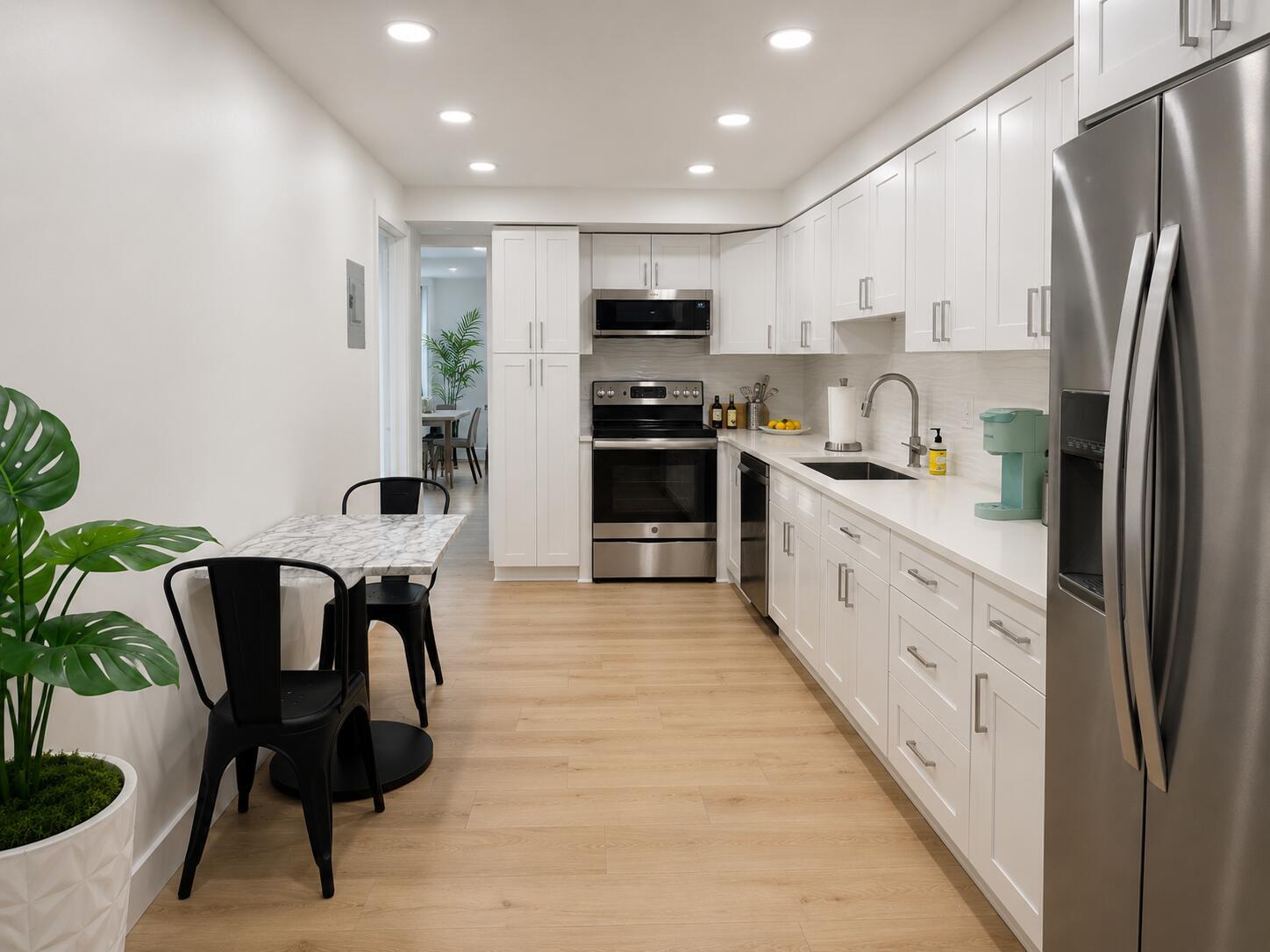 A galley kitchen features white cabinets, stainless steel appliances, and a small marble-topped dining table — 3460 S Ocean Boulevard # 4150, Palm Beach FL 33480, PALM BEACH, FL