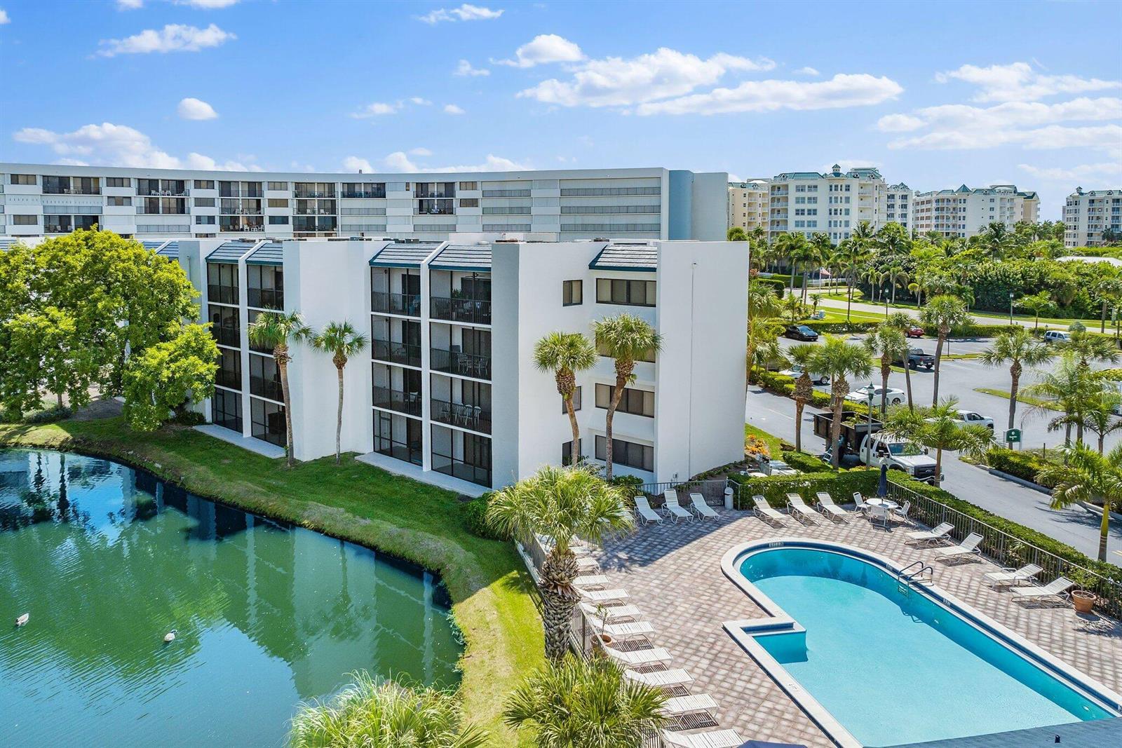 An aerial view of a multi-story apartment building with a swimming pool and a pond — 1605 S Us Highway 1 # B104, Jupiter FL 33477, JUPITER, FL