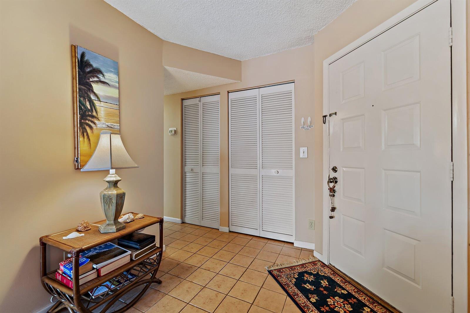 An entryway features a tiled floor, a white front door, and two louvered closet doors — 1605 S Us Highway 1 # B104, Jupiter FL 33477, JUPITER, FL