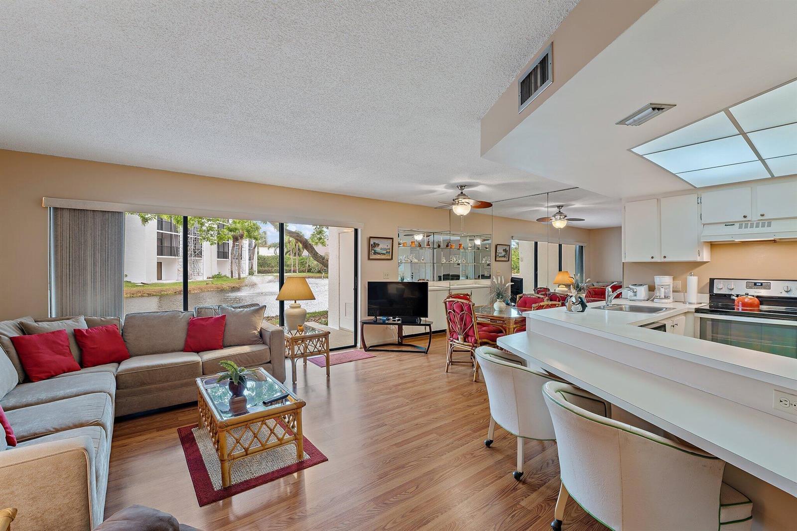 A living room and kitchen area with wood flooring, a sofa, and a water view — 1605 S Us Highway 1 # B104, Jupiter FL 33477, JUPITER, FL
