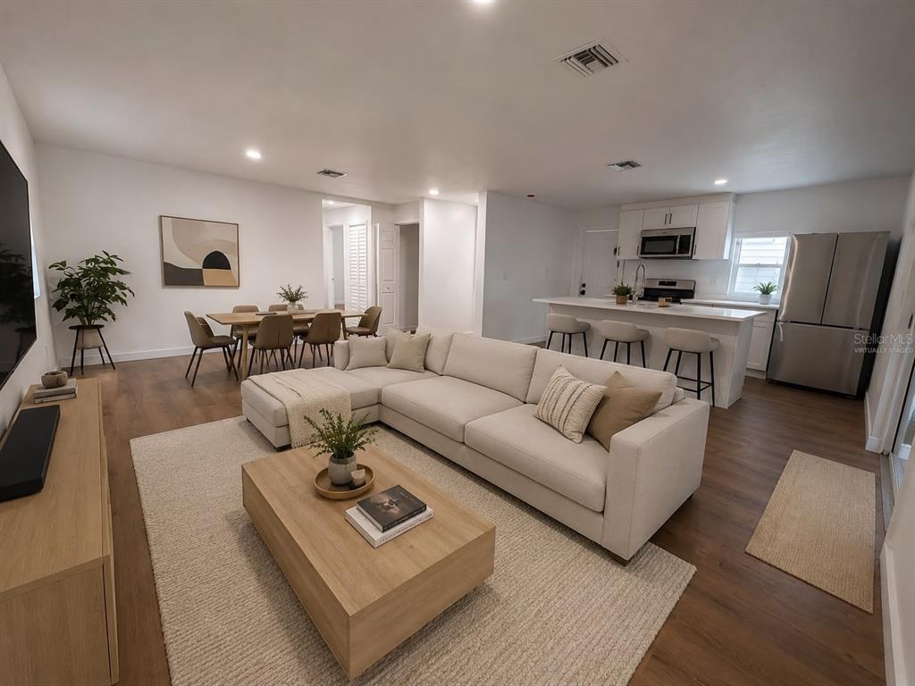 An open-concept living room and kitchen featuring a sectional sofa, dining area, and island — 9212 N BROOKS STREET, TAMPA, FL