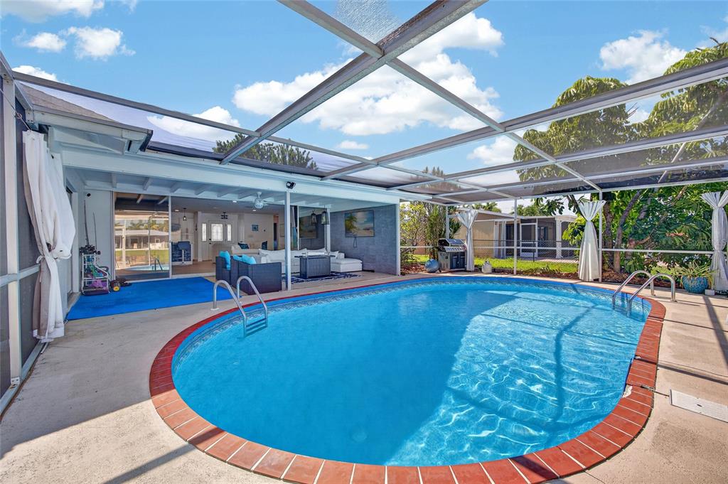 A screened-in patio features a kidney-shaped swimming pool with a red brick border — 3114 SE 18TH AVENUE, CAPE CORAL, FL