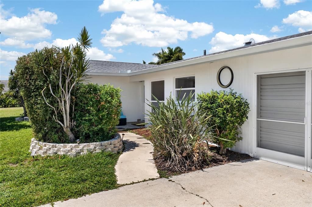 A white exterior house features a concrete walkway, landscaping, and a screened-in porch area — 3114 SE 18TH AVENUE, CAPE CORAL, FL