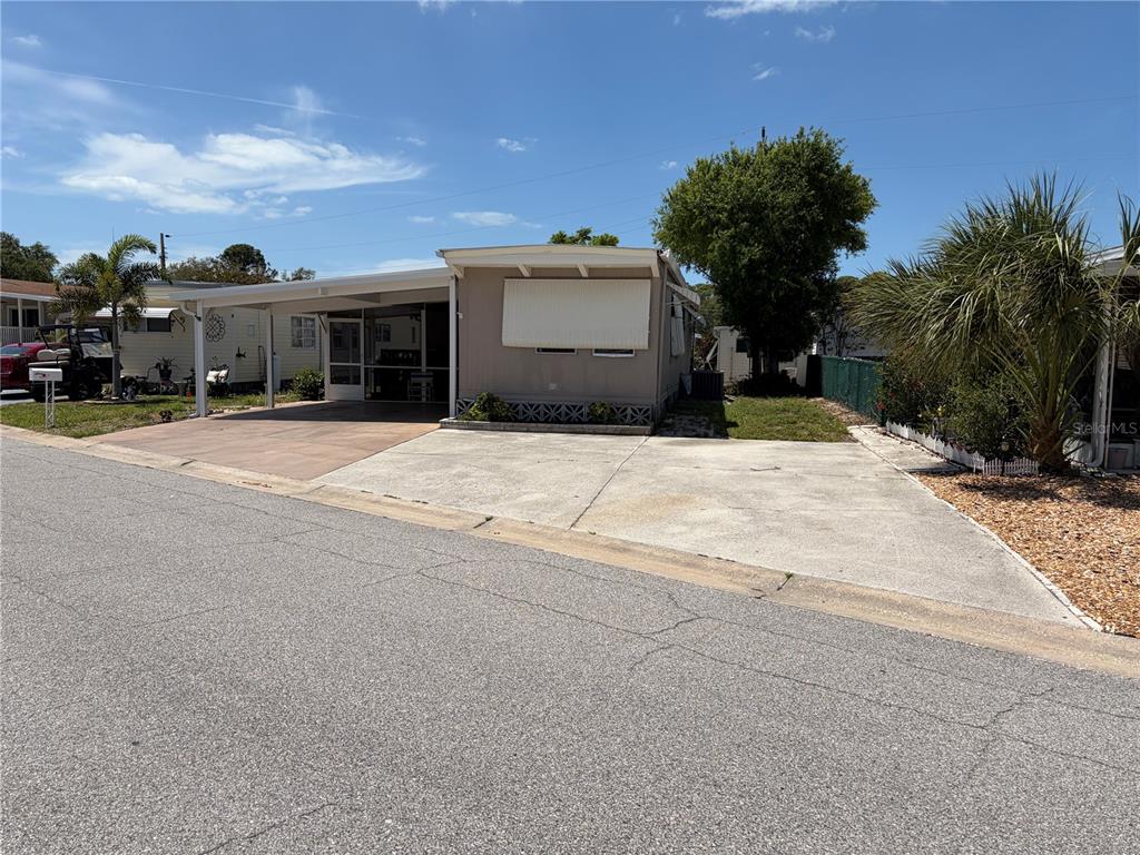 A single-story manufactured home features a concrete driveway, a carport, and a small front yard — 4819 SEA ISLAND AVENUE, SARASOTA, FL