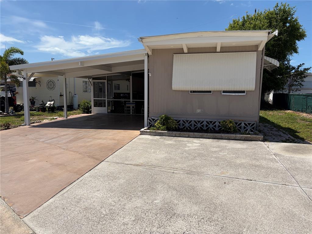 A single-story mobile home features a concrete driveway, a covered carport, and a screened porch — 4819 SEA ISLAND AVENUE, SARASOTA, FL