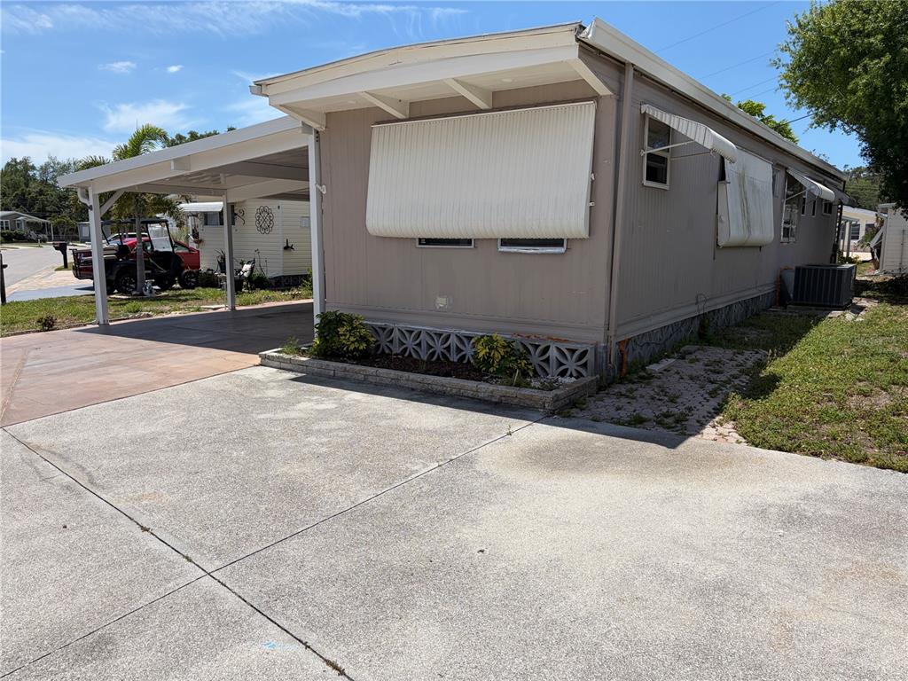 A tan mobile home with a carport, concrete driveway, and decorative concrete block skirting — 4819 SEA ISLAND AVENUE, SARASOTA, FL