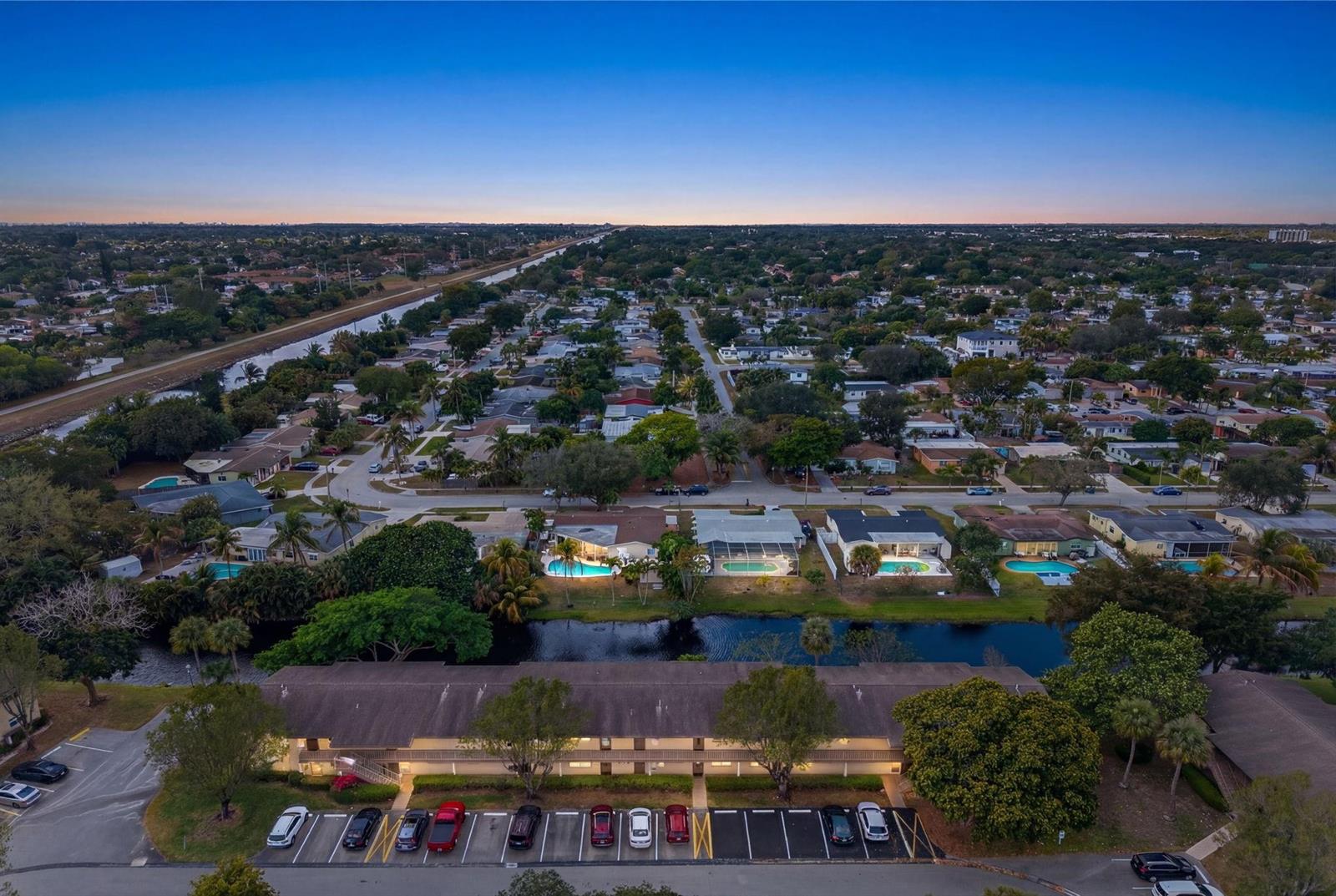 An aerial view shows a residential neighborhood with a canal, swimming pools, and apartment parking — 101 NW 76th Avenue # 102, Margate FL 33063, MARGATE, FL