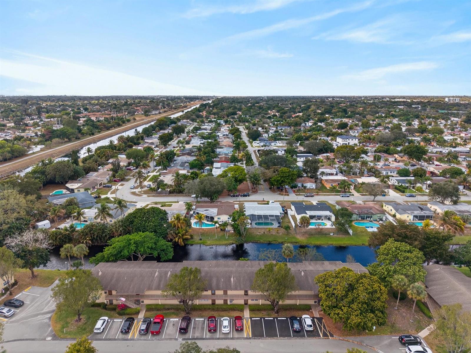 An aerial view shows a residential neighborhood with a canal, swimming pools, and apartment buildings — 101 NW 76th Avenue # 102, Margate FL 33063, MARGATE, FL