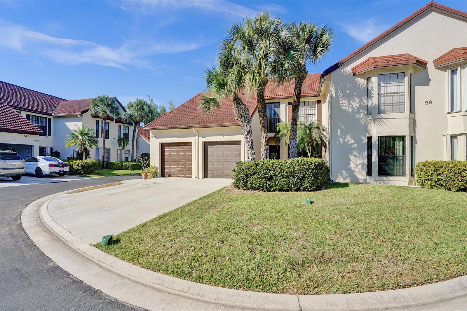 A two-story townhouse with a two-car garage, palm trees, and a manicured lawn — 3068 Lucerne Park Drive, FL 33467, FL