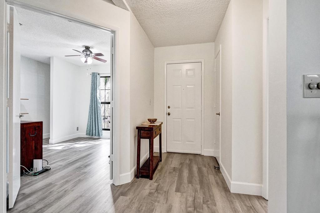 An entryway with light wood-look flooring leads to a white door and an adjacent room — 3068 Lucerne Park Drive, FL 33467, FL
