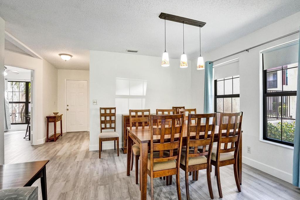 A dining area features a wooden table with chairs, a pendant light, and light flooring — 3068 Lucerne Park Drive, FL 33467, FL