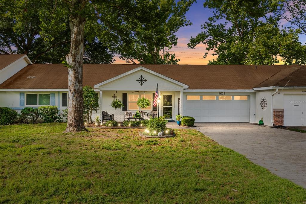 A single-story house with a brown roof, white siding, and a paved driveway at dusk — 8900 SW 97TH LANE ROAD UNIT H, OCALA, FL
