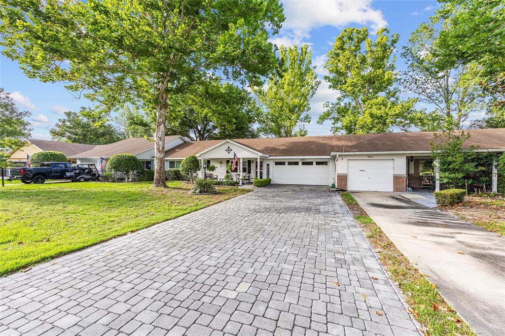 A single-story house with a paved driveway, a two-car garage, and mature trees — 8900 SW 97TH LANE ROAD UNIT H, OCALA, FL
