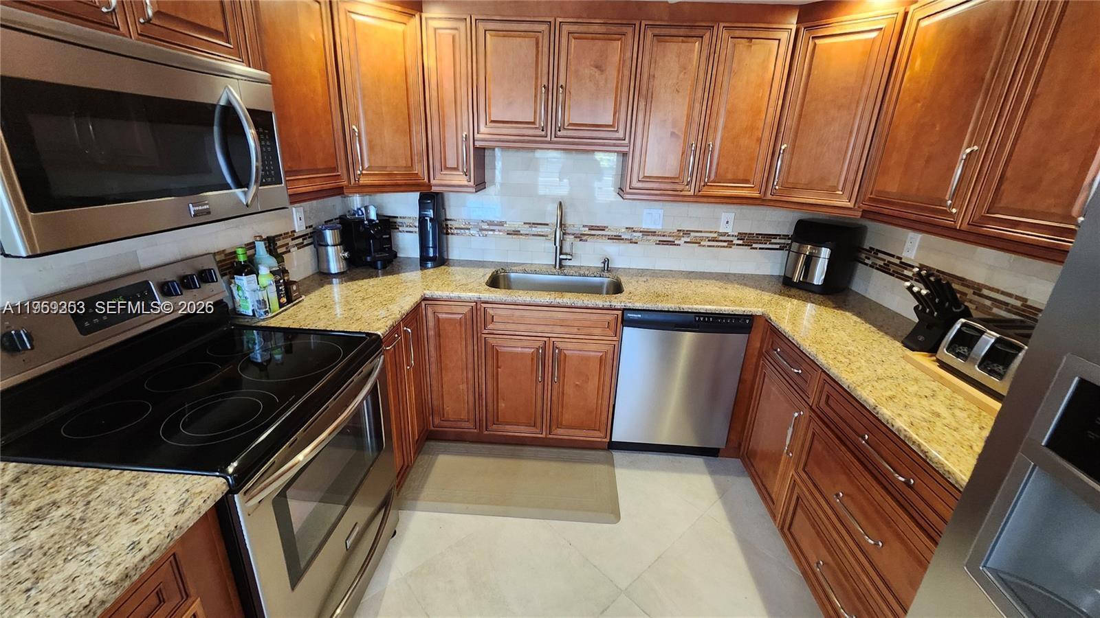 A kitchen features wood cabinets, granite countertops, stainless steel appliances, and a tiled backsplash — 4072 Ventnor P # 4072, Deerfield Beach FL 33442, DEERFIELD BEACH, FL
