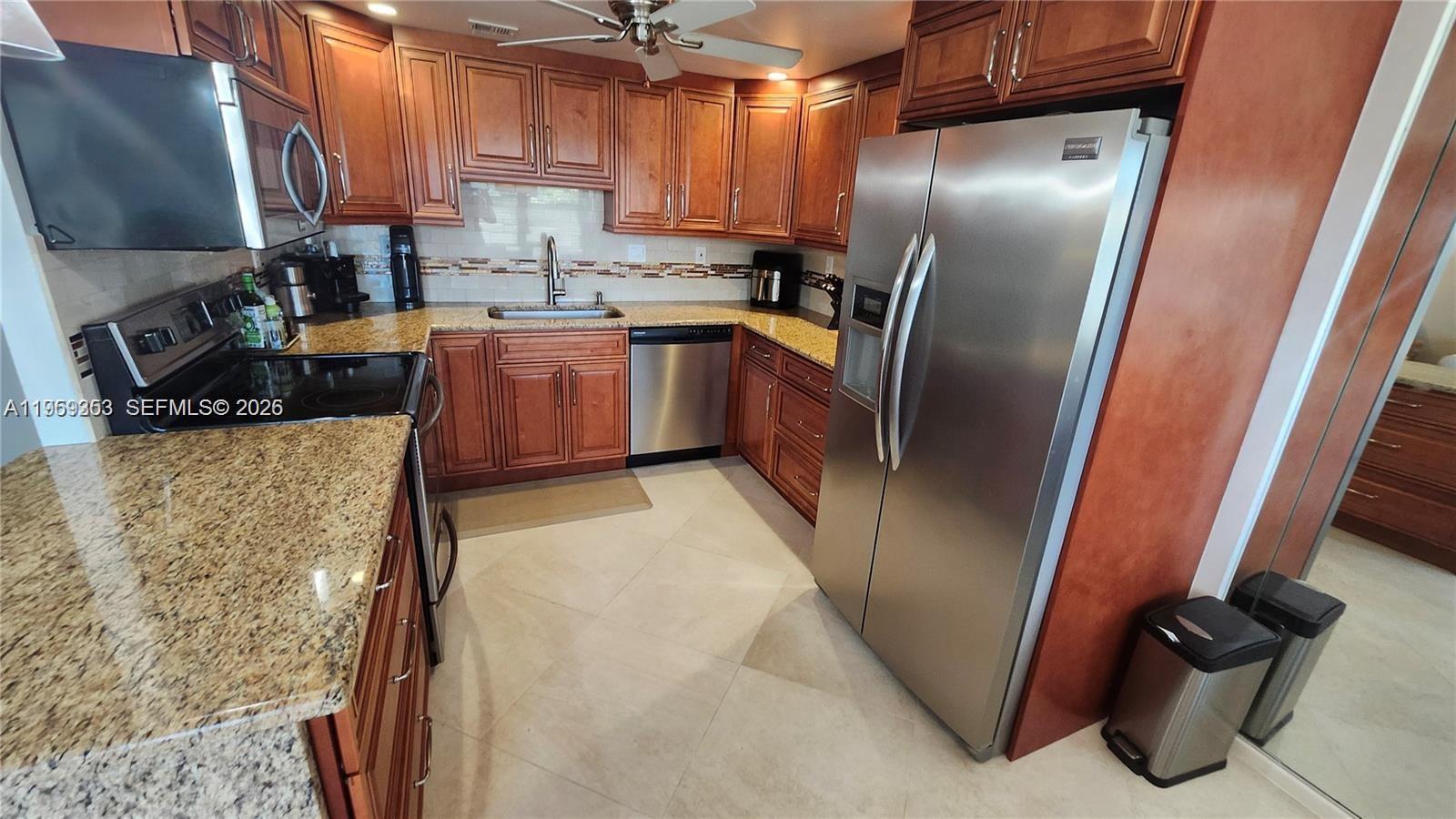 A kitchen features wood cabinets, granite countertops, stainless steel appliances, and tile flooring — 4072 Ventnor P # 4072, Deerfield Beach FL 33442, DEERFIELD BEACH, FL