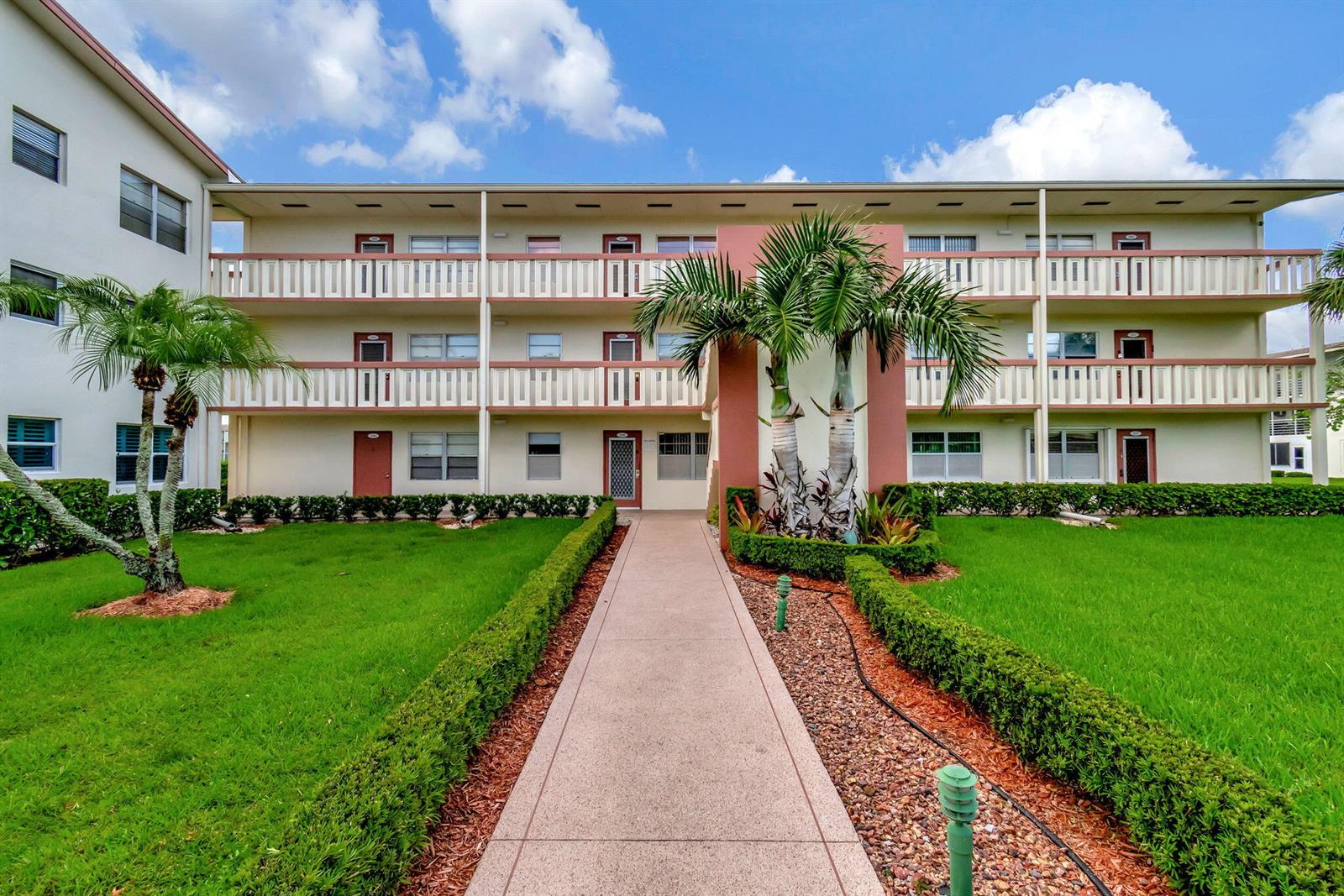 A three-story apartment building with a central walkway, palm trees, and manicured hedges — 339 Preston I, Boca Raton FL 33434, BOCA RATON, FL