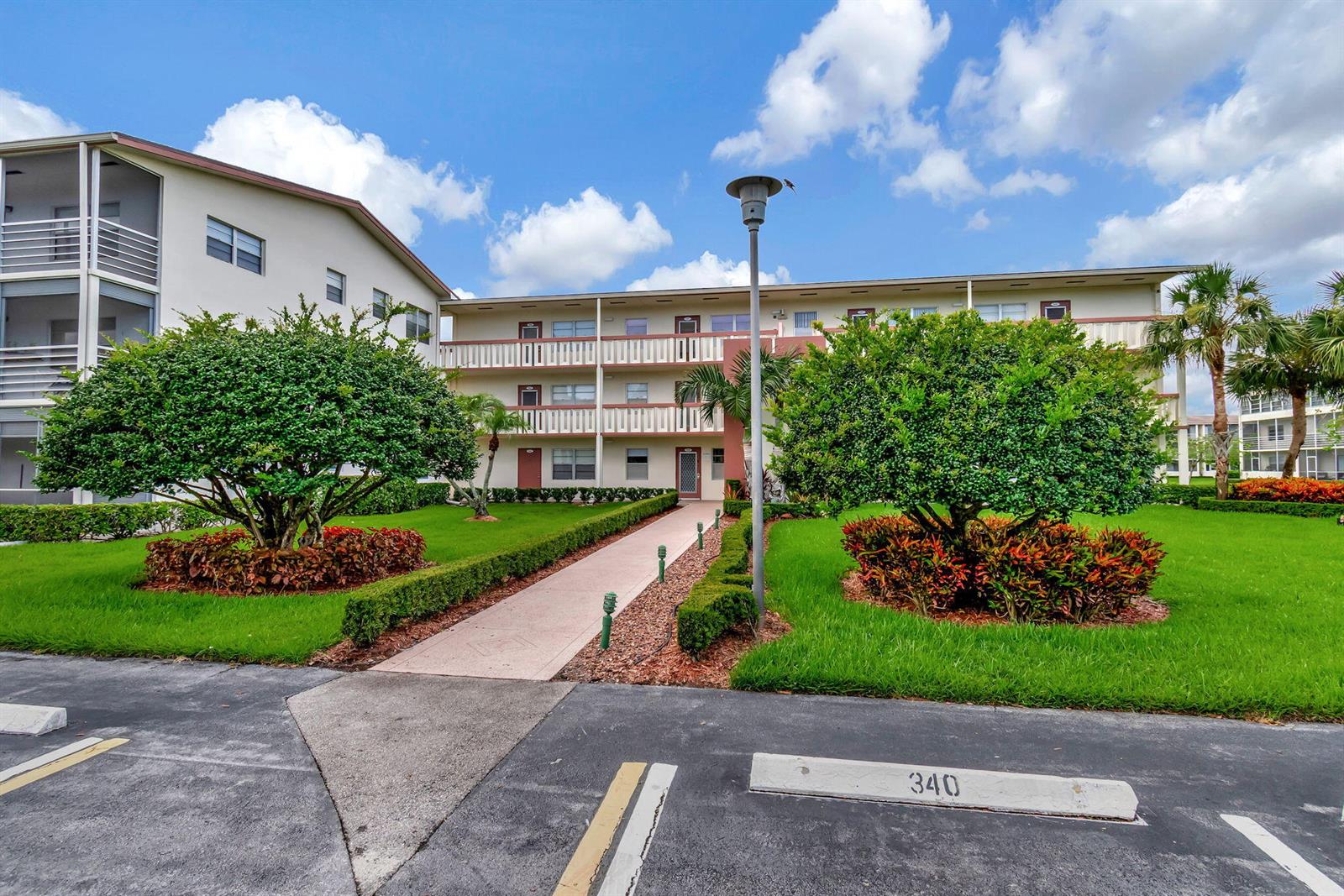 A three-story apartment building with a walkway, landscaping, and a parking space numbered 340 — 339 Preston I, Boca Raton FL 33434, BOCA RATON, FL