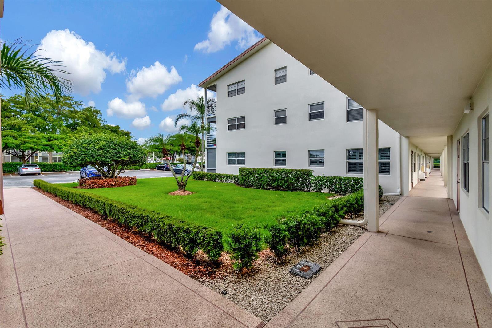 A view of a multi-story apartment building exterior with a landscaped lawn and walkway — 339 Preston I, Boca Raton FL 33434, BOCA RATON, FL
